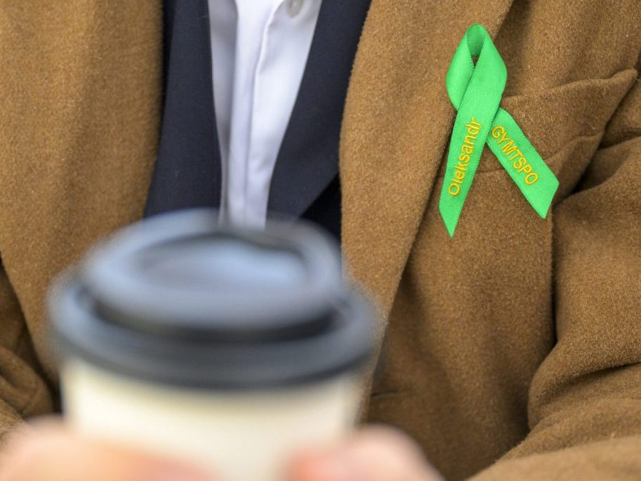 Študent s kávou a maturitnou stužkou.