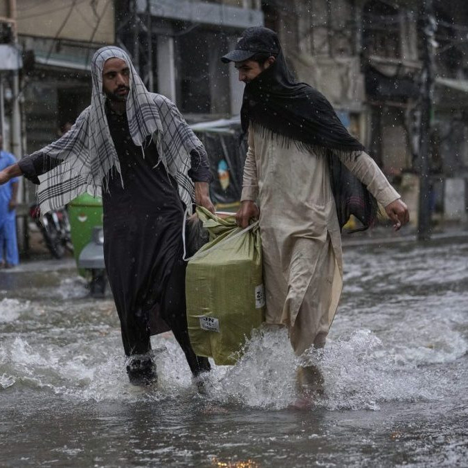 Muži počas monzúnových dažďov v Pakistane.
