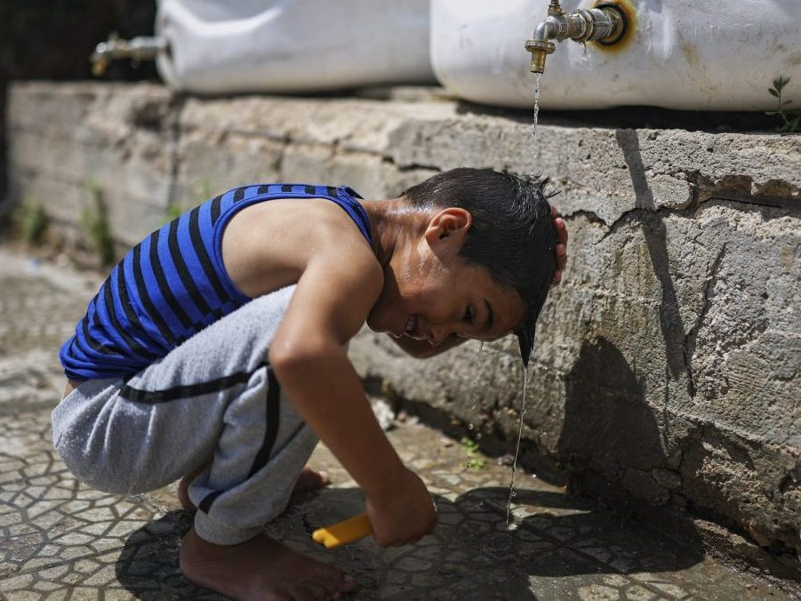 Sýrsky chlapec sa ochladzuje vodou z cisterny.