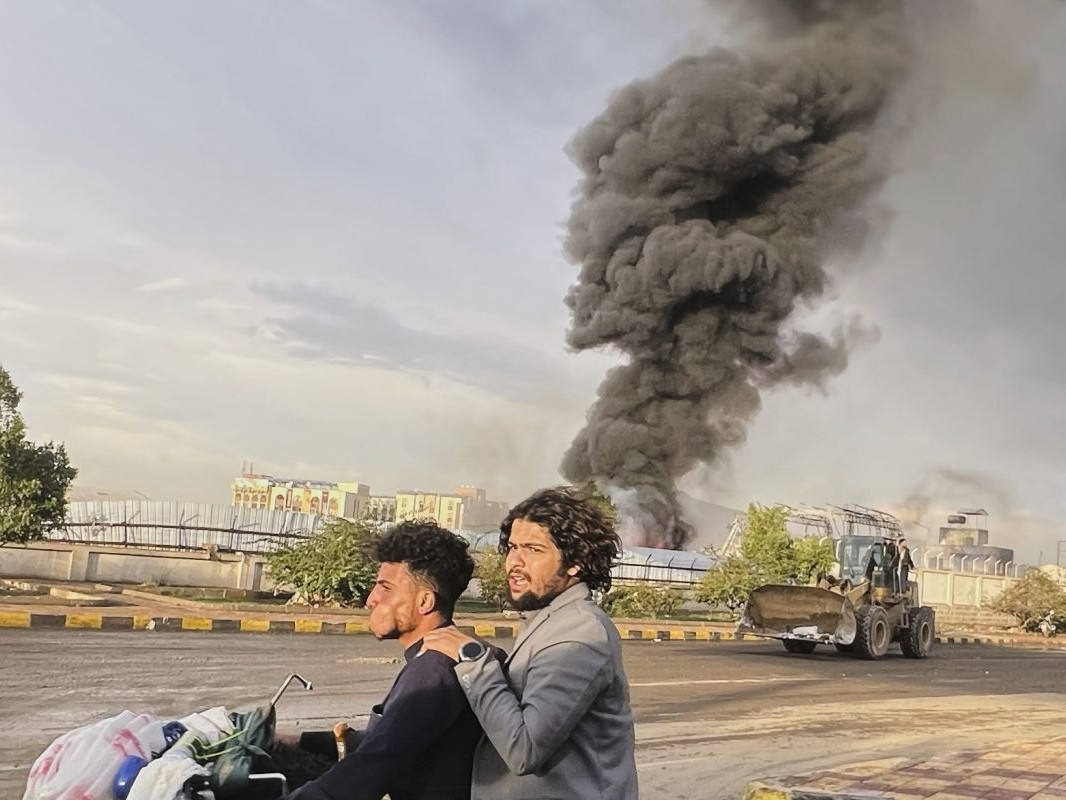 Na snímke muži jazdia na motorke počas leteckého útoku Izraelu na jemenské hlavné mesto Saná.
