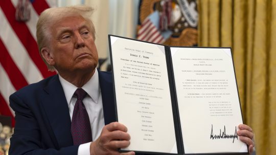Na snímke je Donald Trump držiaci dekrét počas pózovania pre fotografov.