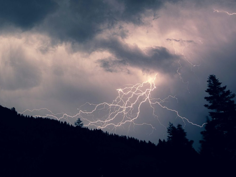 Na snímke sú blesky nad kopcami a lesom.