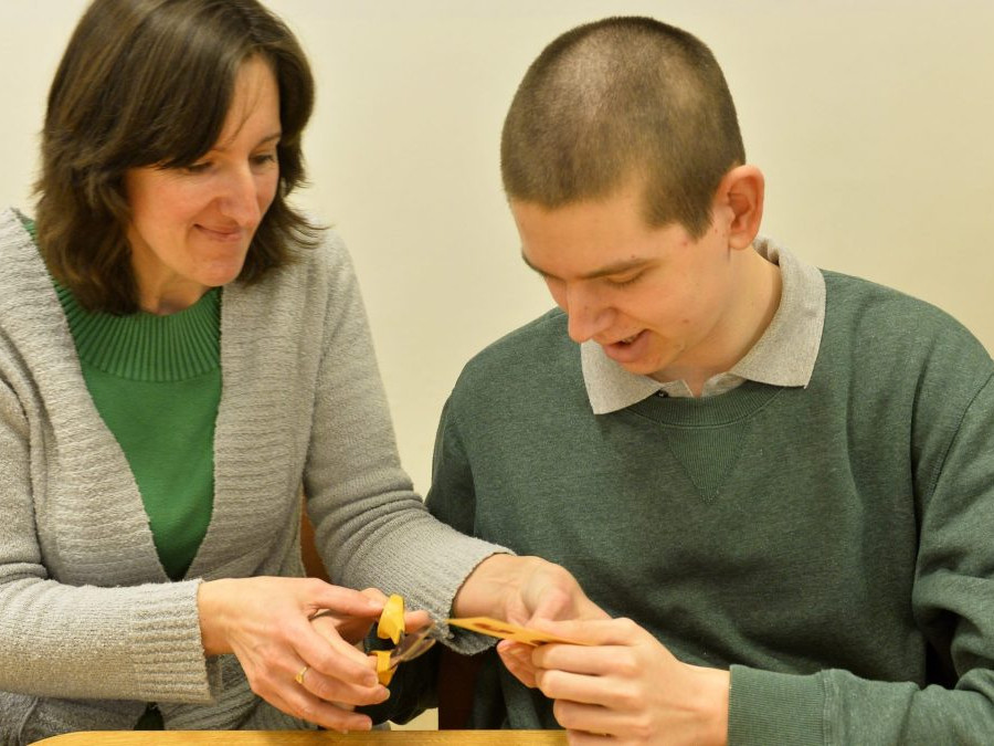 Na snímke vpravo autista za pomoci opatrovateľky pracuje v tvorivej dielni v domove sociálnych služieb.