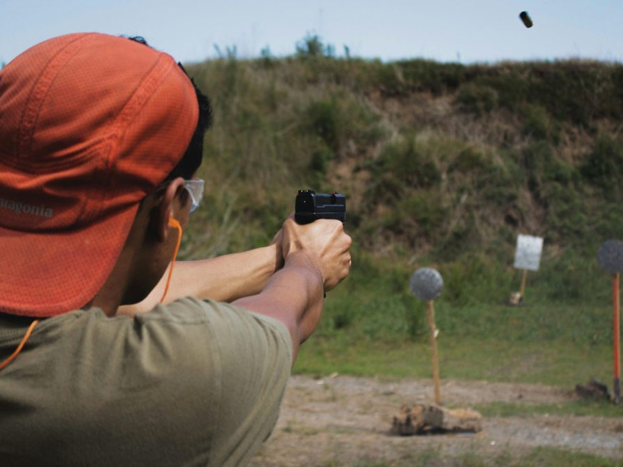 Muž strieľa zbraňou na terče na strelnici.
