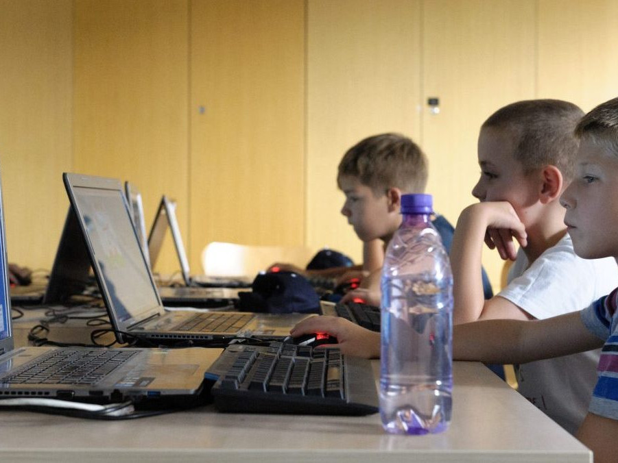 Ilustračná snímka detí pracujúcich s počítačmi.