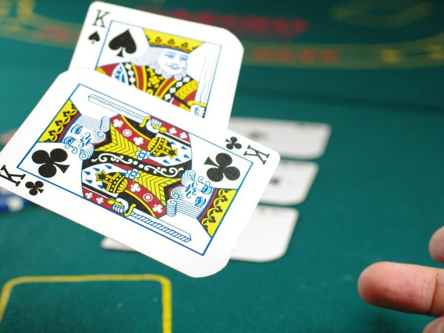 Na snímke je herný stôl v kasíne, osoba hádže dvojicu kariet.