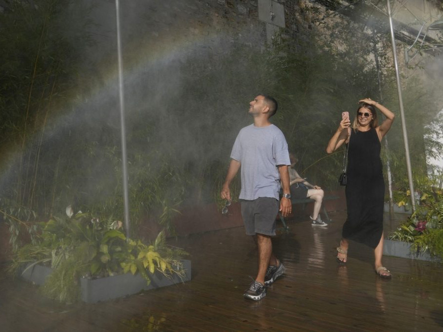 Ľudia sa ochladzujú pod rozprašovačom.