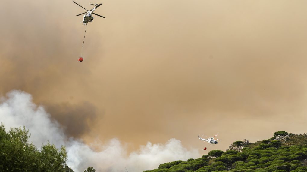 Na snímke je dvojica helikoptér, ktoré zhadzujú vodu na požiarom postihnuté lesy v Španielsku.