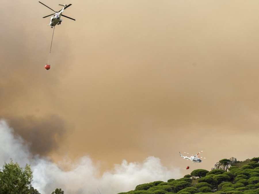 Na snímke je dvojica helikoptér, ktoré zhadzujú vodu na požiarom postihnuté lesy v Španielsku.