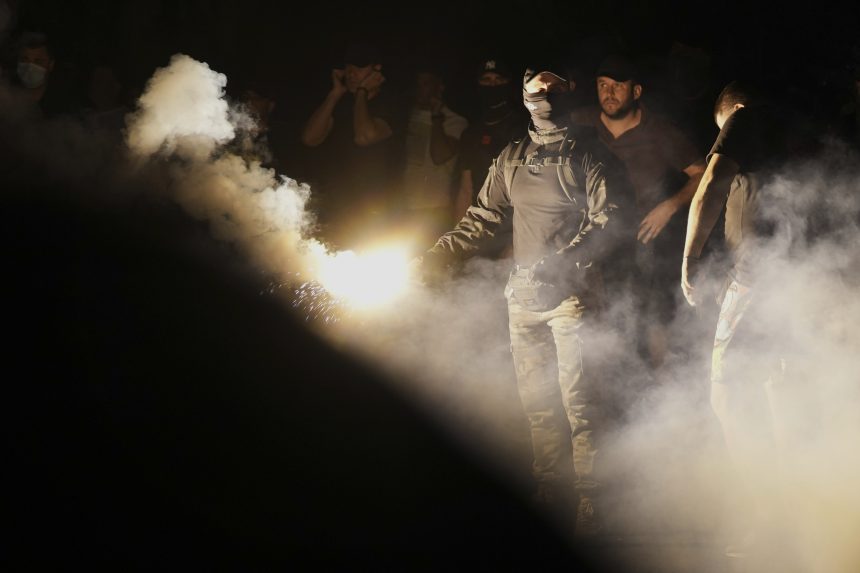 Demonštranti počas protivládnych protestov, uprostred muž so zapálenou svetlicou.