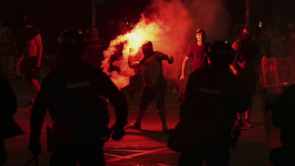 Demonštranti počas protivládnych protestov, uprostred muž so zapálenou svetlicou.