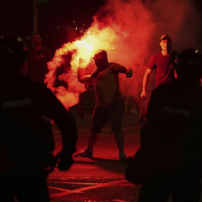 Demonštranti počas protivládnych protestov, uprostred muž so zapálenou svetlicou.