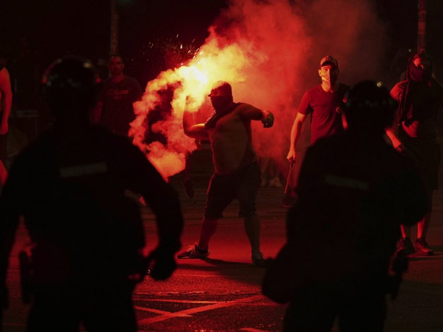 Demonštranti počas protivládnych protestov, uprostred muž so zapálenou svetlicou.