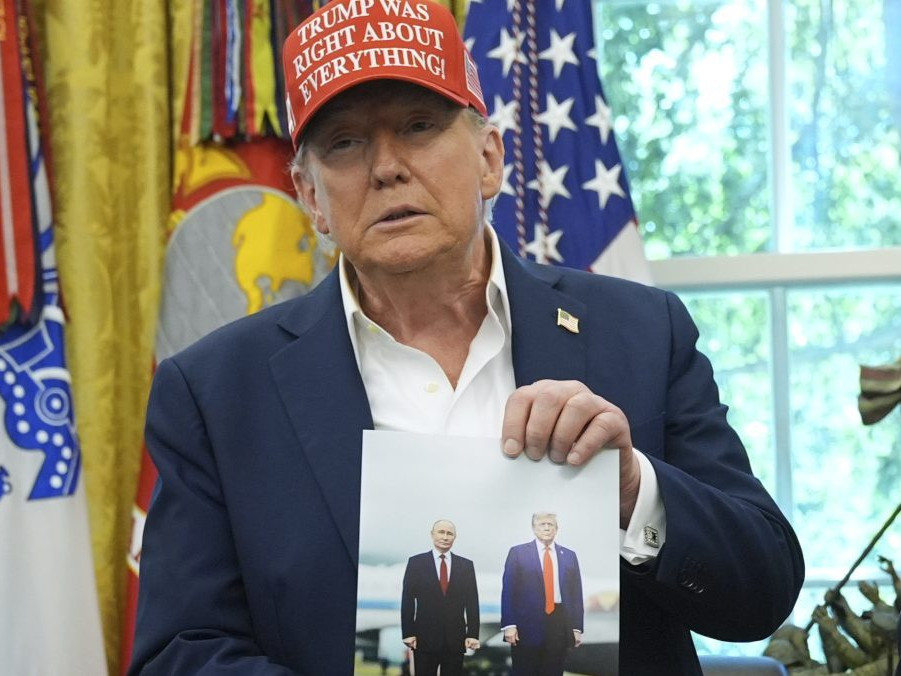 Donald Trump drží v rukách fotografiu seba a prezidenta Vladimira Putina zo samitu na Aljaške.