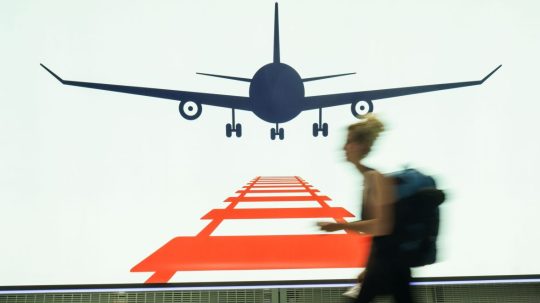 Na archívnej snímke zo 4. júla 2022 žena prechádza na frankfurtskom letisku popri reklamnej tabuli.