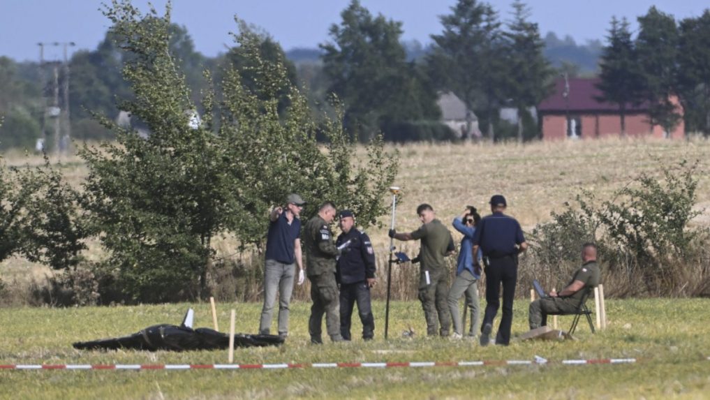Poľskí policajti a vojaci zabezpečujú miesto, kde dopadli trosky zostreleného ruského dronu.