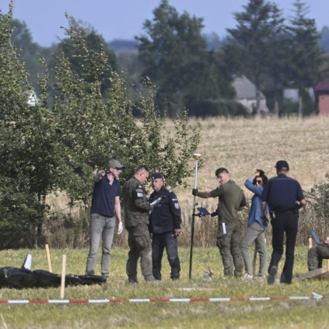 Poľskí policajti a vojaci zabezpečujú miesto, kde dopadli trosky zostreleného ruského dronu.