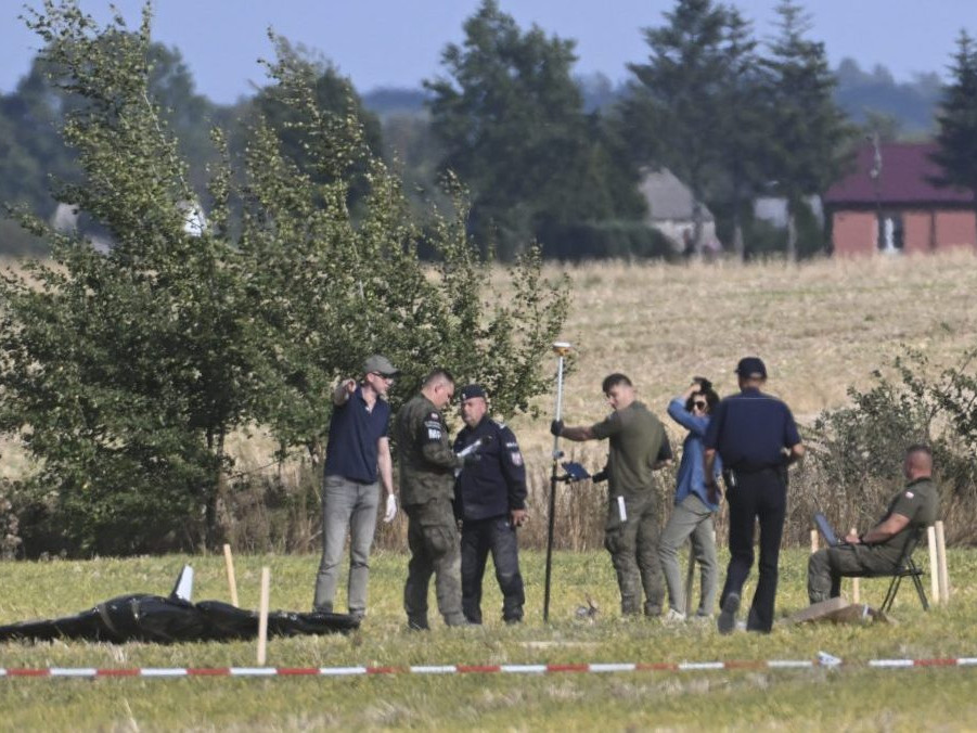 Poľskí policajti a vojaci zabezpečujú miesto, kde dopadli trosky zostreleného ruského dronu.