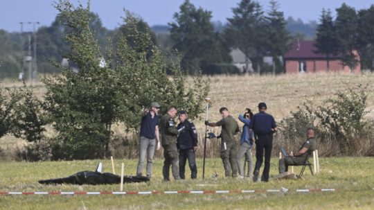 Poľskí policajti a vojaci zabezpečujú miesto, kde dopadli trosky zostreleného ruského dronu.