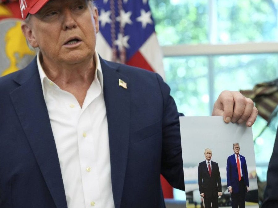 Na snímke Trump drží v ruke fotografiu zo stretnutia s Putinom.