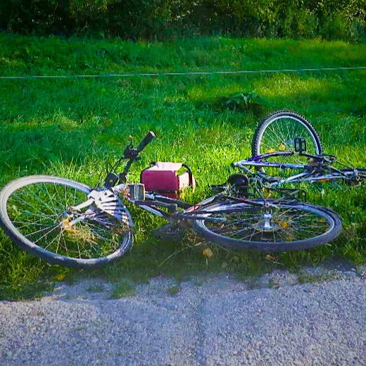 Na snímke je padnutý horský bicykel na trávniku pri ceste.