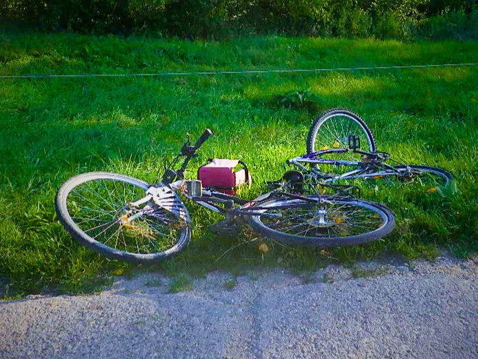 Na snímke je padnutý horský bicykel na trávniku pri ceste.