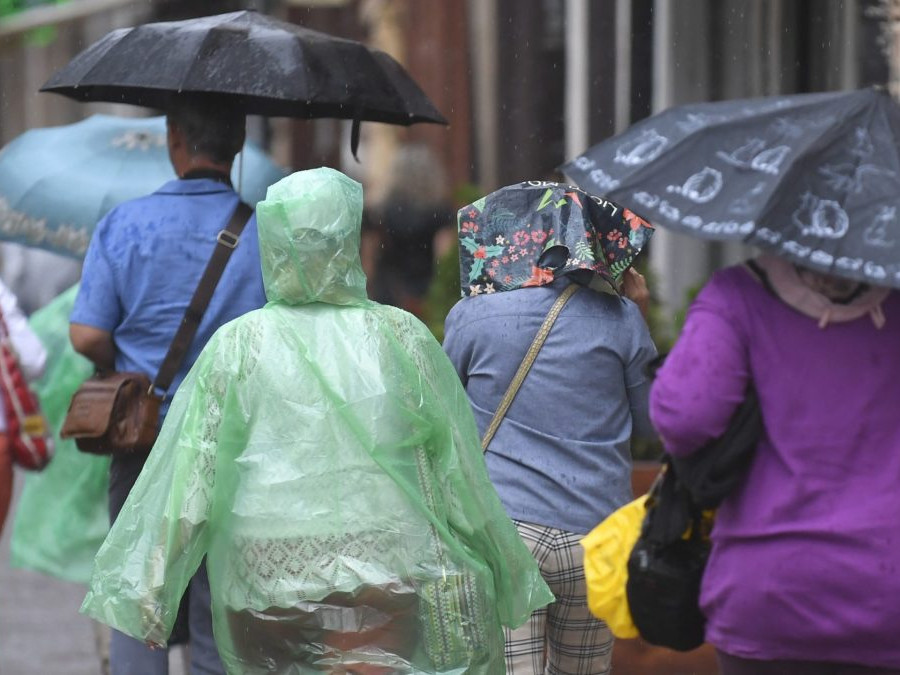 Na snímke sú osoby v uliciach Košíc počas dažďa oblečení pršiplášťami, niektorí majú nad hlavami roztvorené dáždniky.