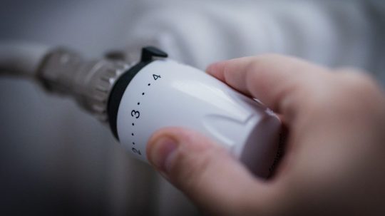 Ruka na termostatickej hlavici radiátora.