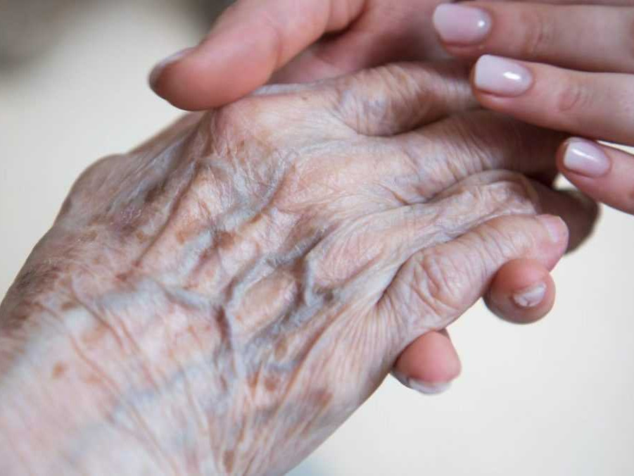 Žena držiaca ruky seniorky.