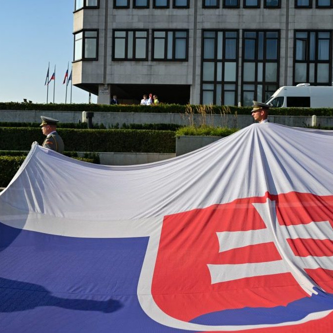 Príslušníci čestnej stráže držia slovenskú vlajku.