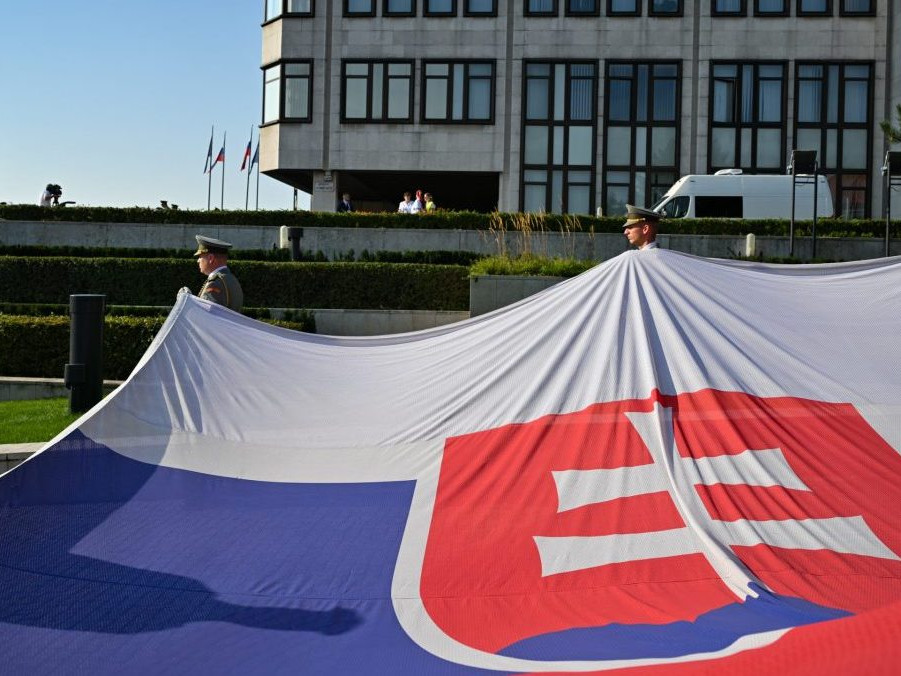 Príslušníci čestnej stráže držia slovenskú vlajku.