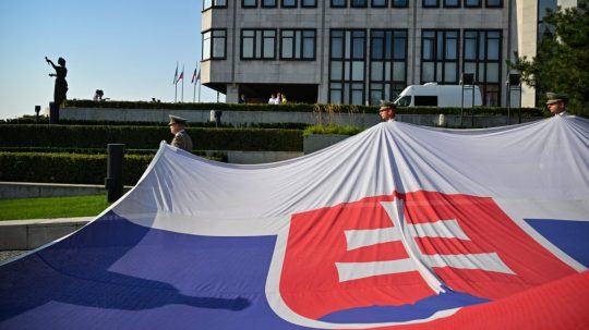 Príslušníci čestnej stráže držia slovenskú vlajku.