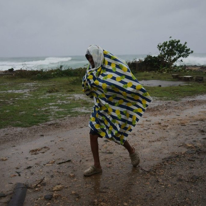 Muž kráča v daždi pred príchodom hurikánu Melissa.