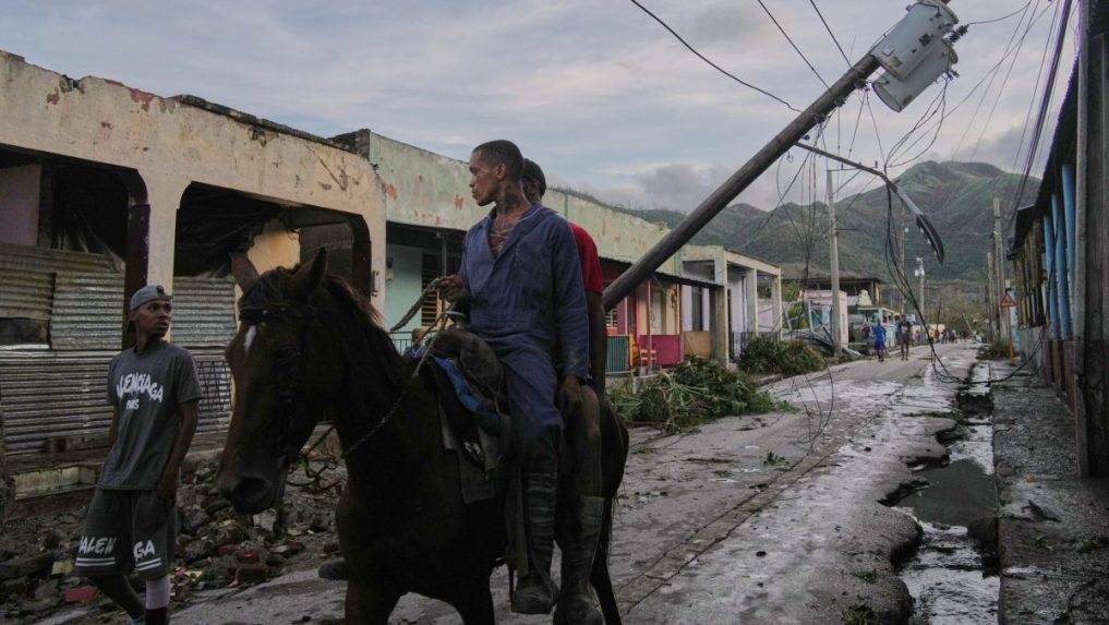 Muži na koni v uliciach El Cobre na Kube po hurikáne Melissa.