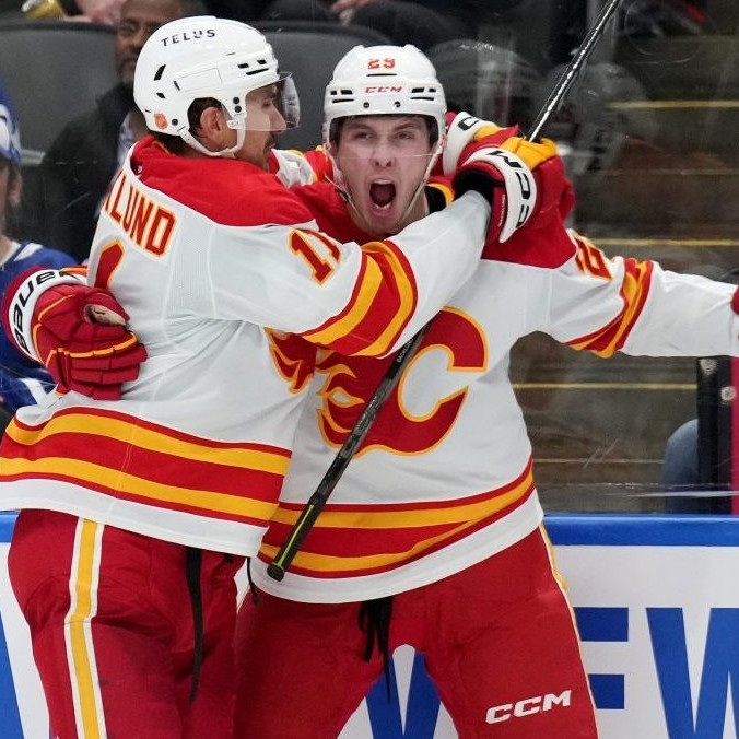 Slovenský útočník Samuel Honzek z Calgary Flames sa teší z gólu s Mikaelom Backlundom.