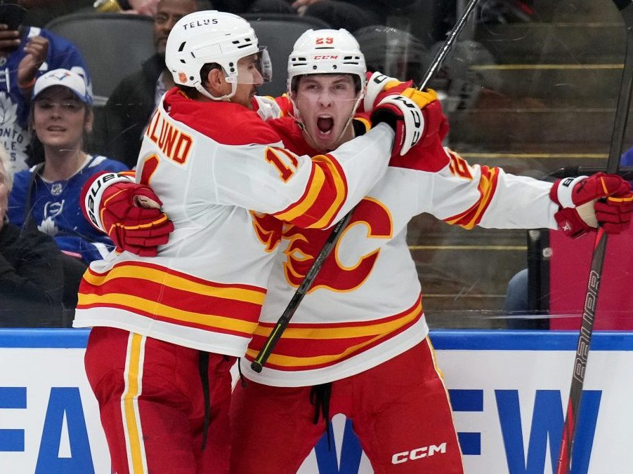 Slovenský útočník Samuel Honzek z Calgary Flames sa teší z gólu s Mikaelom Backlundom.