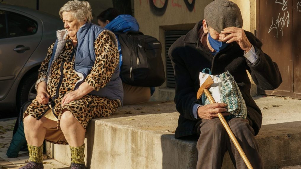 Na snímke šokovaní obyvatelia sedia pred poškodeným činžiakom po výbuchu v obytnej štvrti v Bukurešti.