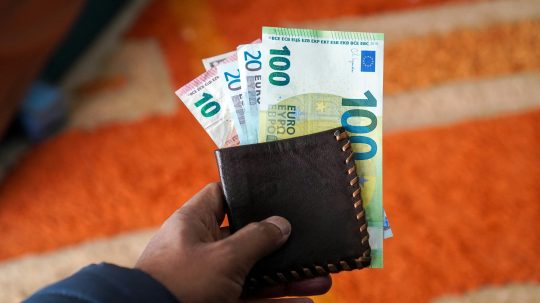 Na snímke osoba s peňaženkou, z ktorej trčia eurobankovky.