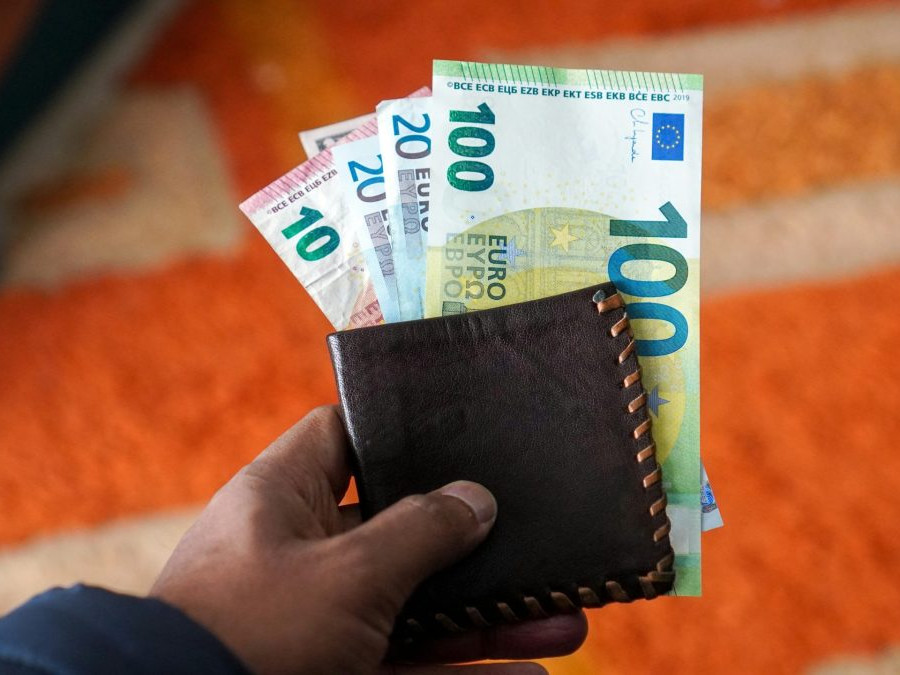 Na snímke osoba s peňaženkou, z ktorej trčia eurobankovky.