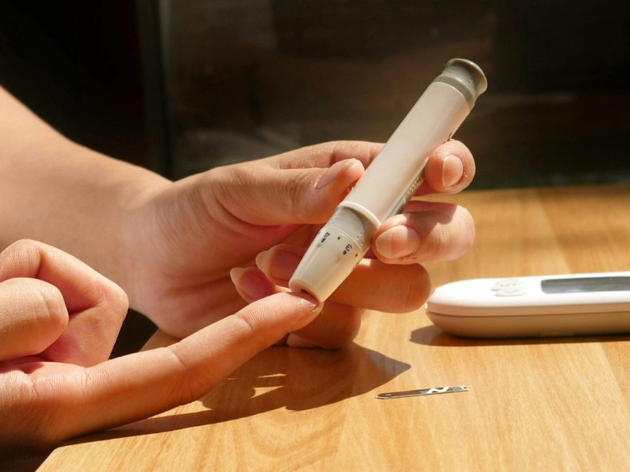 Osoba si meria hladinu inzulínu krvi pomocou pera.