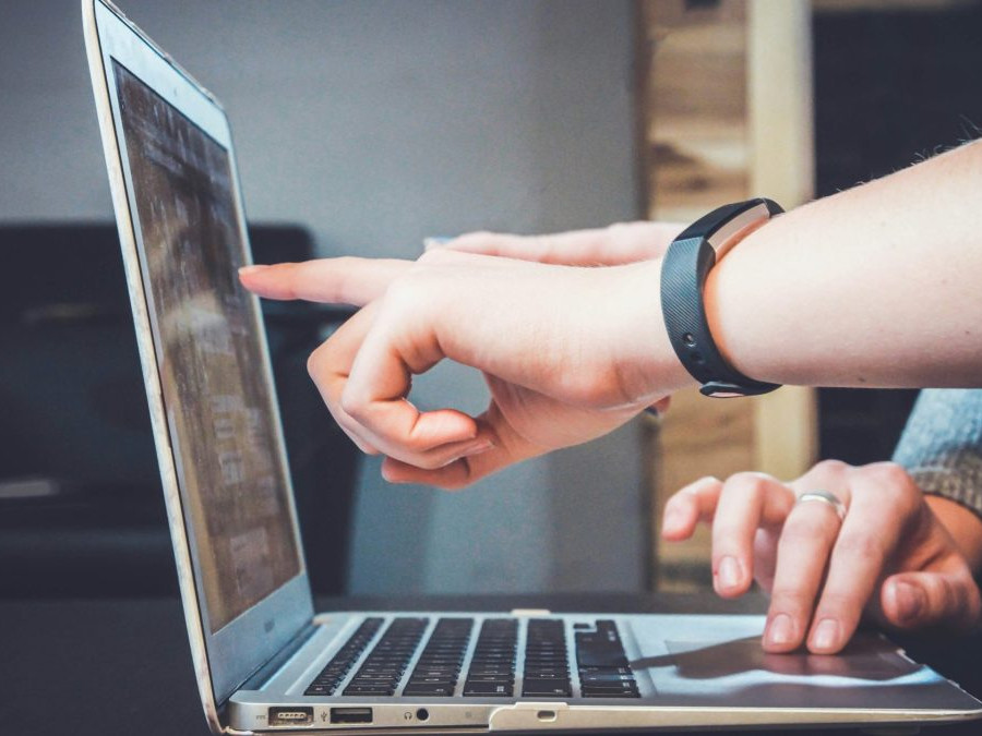 Na snímke dve osoby pracujú s notebookom, jedna z nich ukazuje prstom na obrazovku.