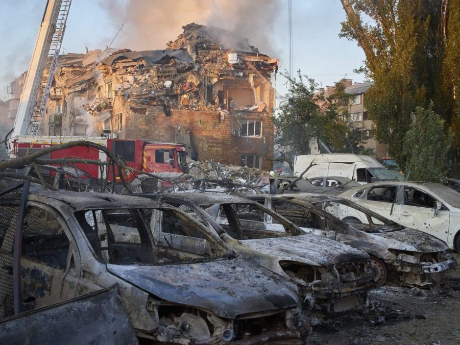 Na snímke zničené autá a budova po ruskom útoku v Kyjeve.