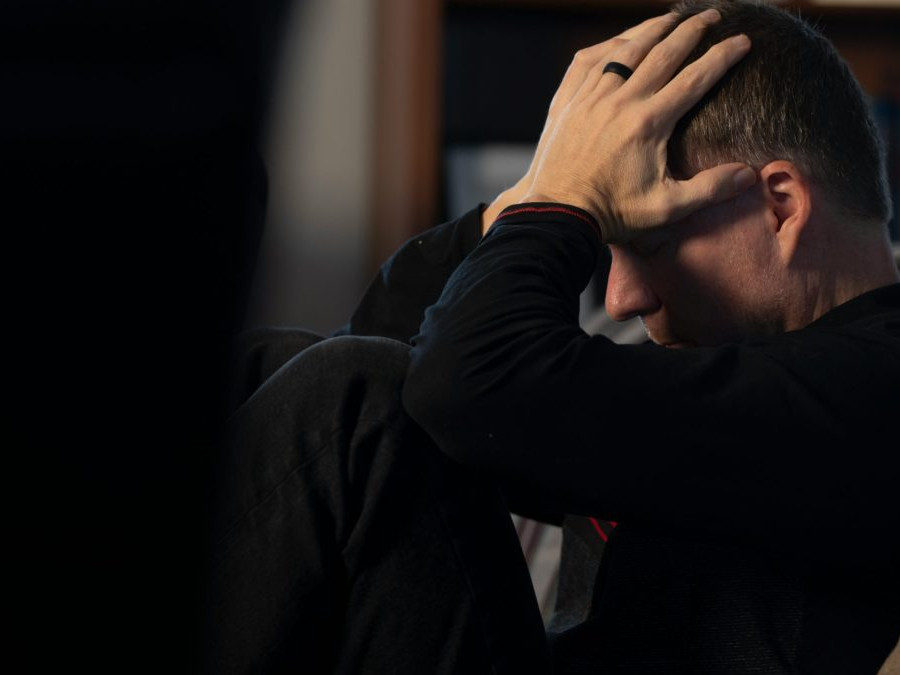 Osoba v tmavom oblečení sa drží za hlavu.