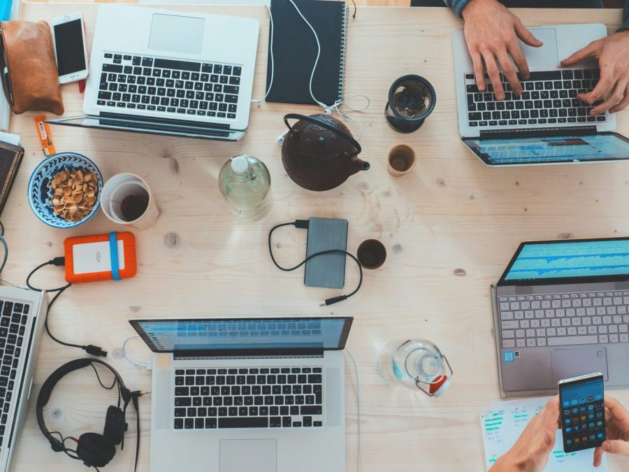 Osoby pracujú s notebookmi a telefónmi na stole.