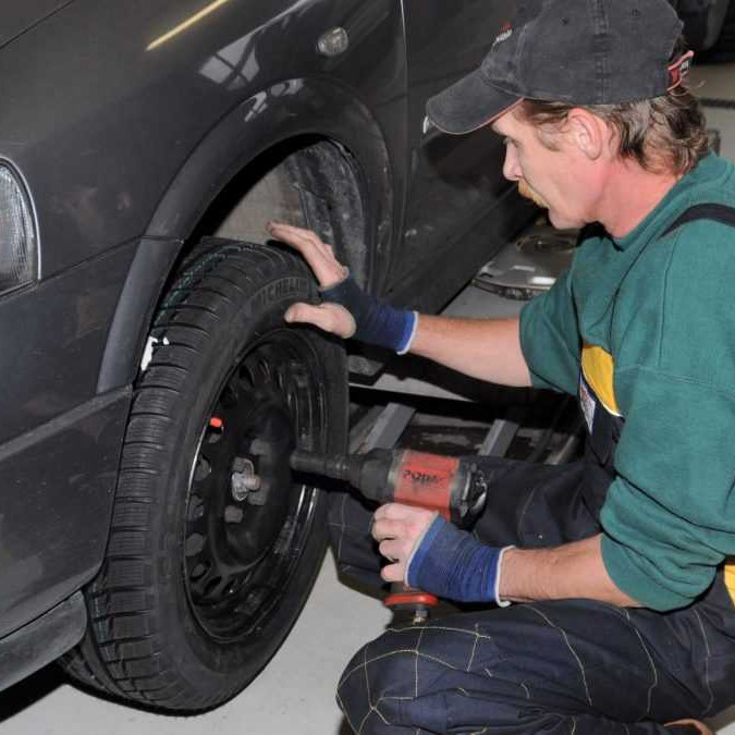 Pracovník autoservisu prezúva pneumatiky na vozidle.