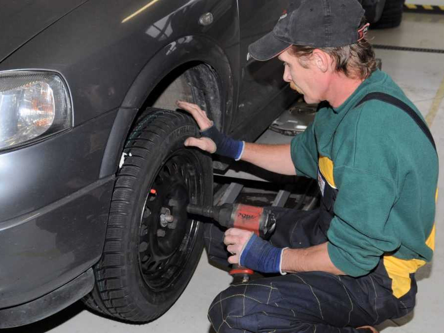 Pracovník autoservisu prezúva pneumatiky na vozidle.