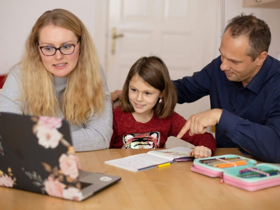 Rodičia sa pri stole učia s dieťaťom.