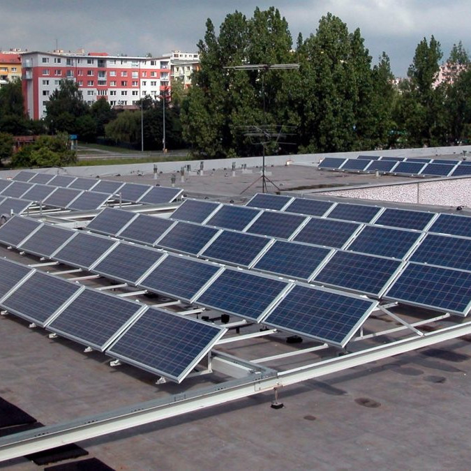 Na snímke solárne panely na plochej streche budovy, v pozadí paneláky.