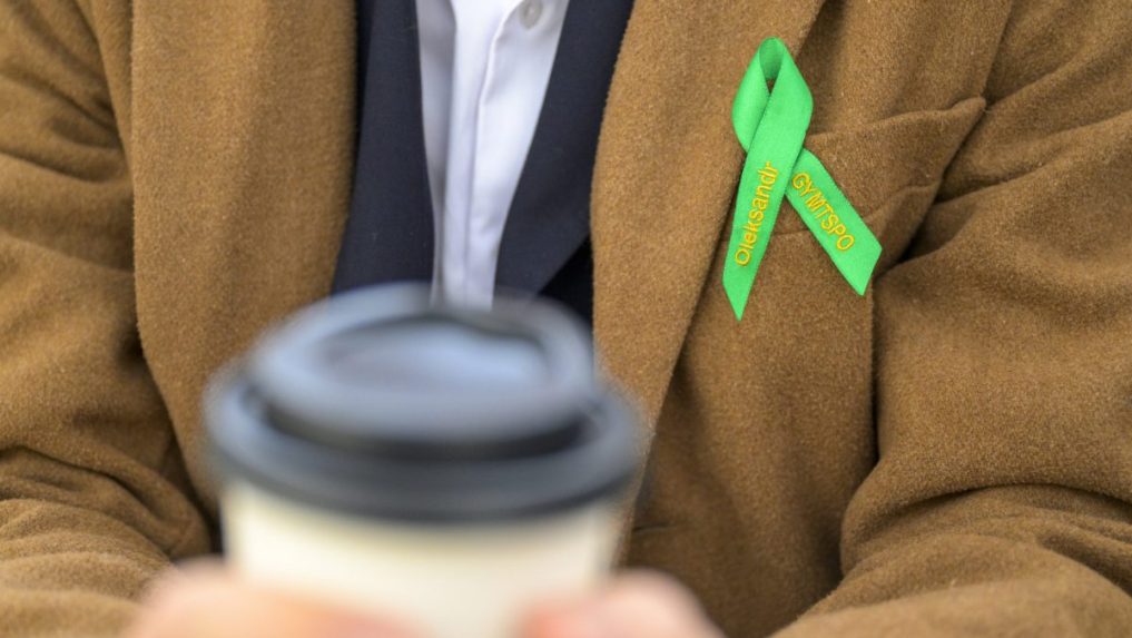 Študent s kávou a maturitnou stužkou.