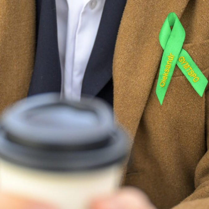 Študent s kávou a maturitnou stužkou.